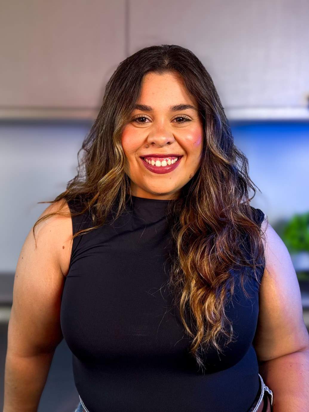 Larissa Ferreira, a fundadora, sorrindo, de cabelo comprido ondulado e blusa preta